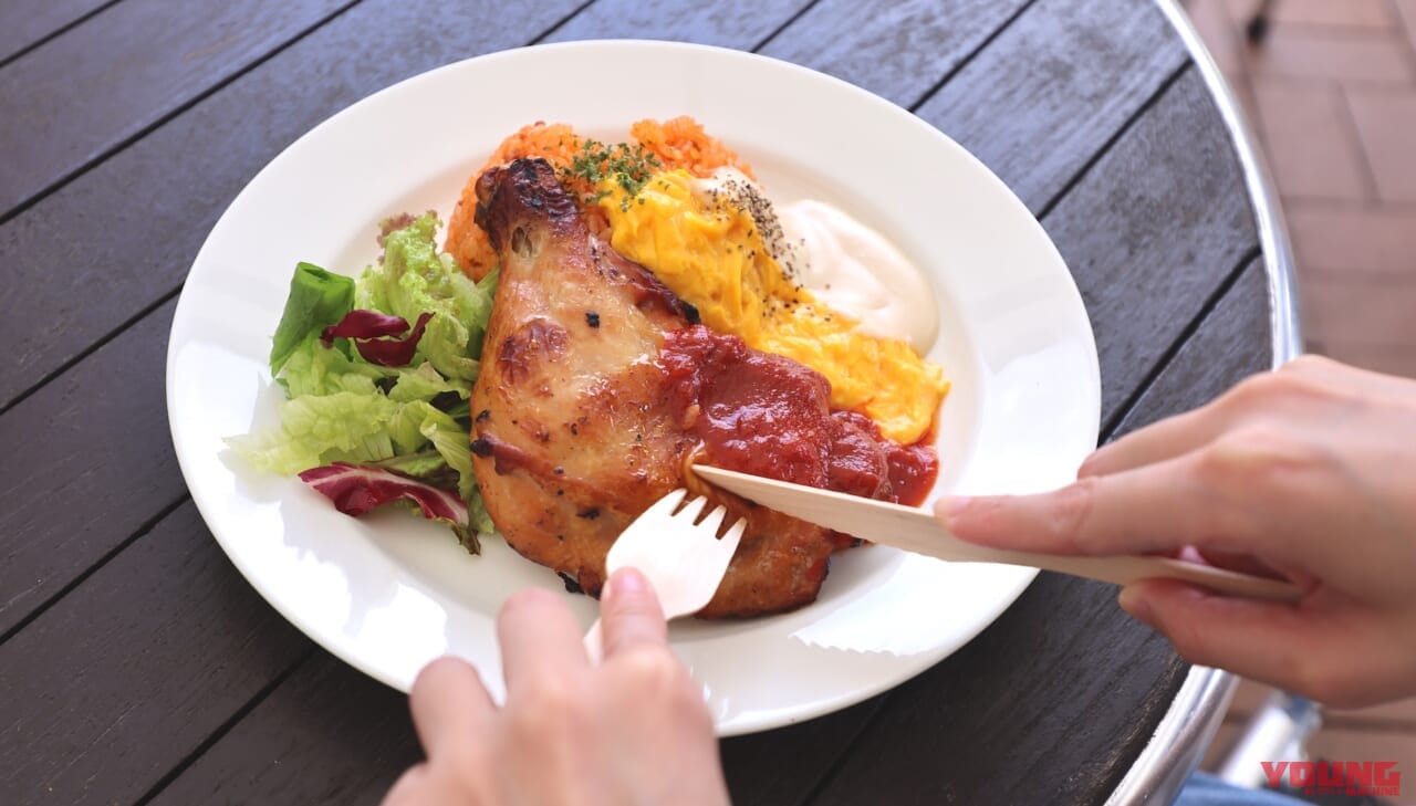 ナイフとフォークでチキンレッグを切り分けて食事する写真|【MotoGP日本GP 10/4~6開催!】会場限定グルメをひと足先にレポート!