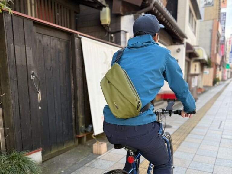 QUICK PACK Traspoを背負って自転車に乗っている画像｜「これ神アイテムでは？」「ありそうでなかった…」便利機能を搭載で、防水性能も高くカラバリ豊富。手放せなくなること必至のバッグを紹介！