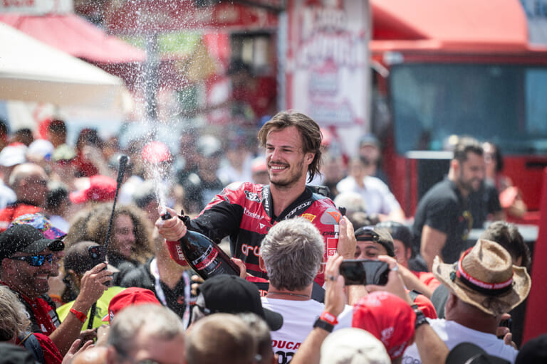 『レース・オブ・チャンピオンズ』を制したのはWSBKライダーのニッコロ・ブレガ。祝福のシャンパンを観客たちと分け合った。(写真提供:ドゥカティ)|来場12万人、パレードは驚異の18km!ドゥカティ100周年記念の『WDW2026』が史上最高のド迫力【マルケス、バニャイア、ストーナーも】