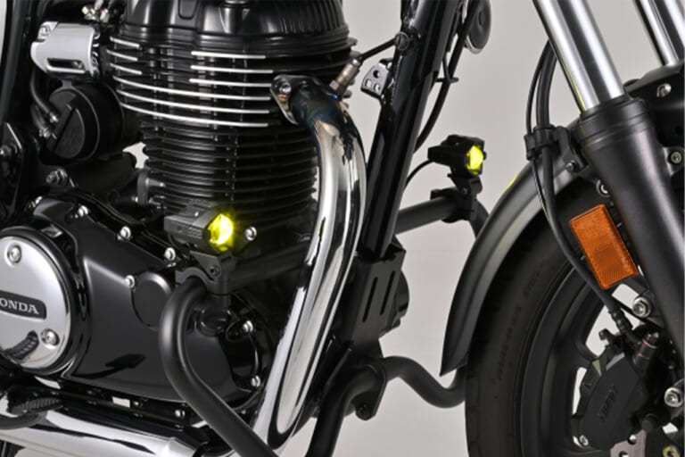 バイクのエンジンガードのパイプに装着した、デイトナのLEDフォグランプユニット プレシャスレイ スモール イエロー（サイドからの写真）｜「スイッチONで明らかに違いを感じる…」あらゆる車種に取付OK。コンパクトボディながら1700ルーメンで視界を確保する［デイトナ・LEDフォグランプユニット プレシャスレイ スモール］