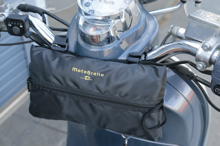 収納状態のモトブレラをベスパ lxv125のハンドル部分に装着した状態の写真｜「マジ？ 車体温度53℃→30℃」簡単装着なのに効果がスゴい…。実際に購入して装着したら手放せなくなった！ 外出先で便利！［バイク用ちょい掛けカバー・モトブレラ］